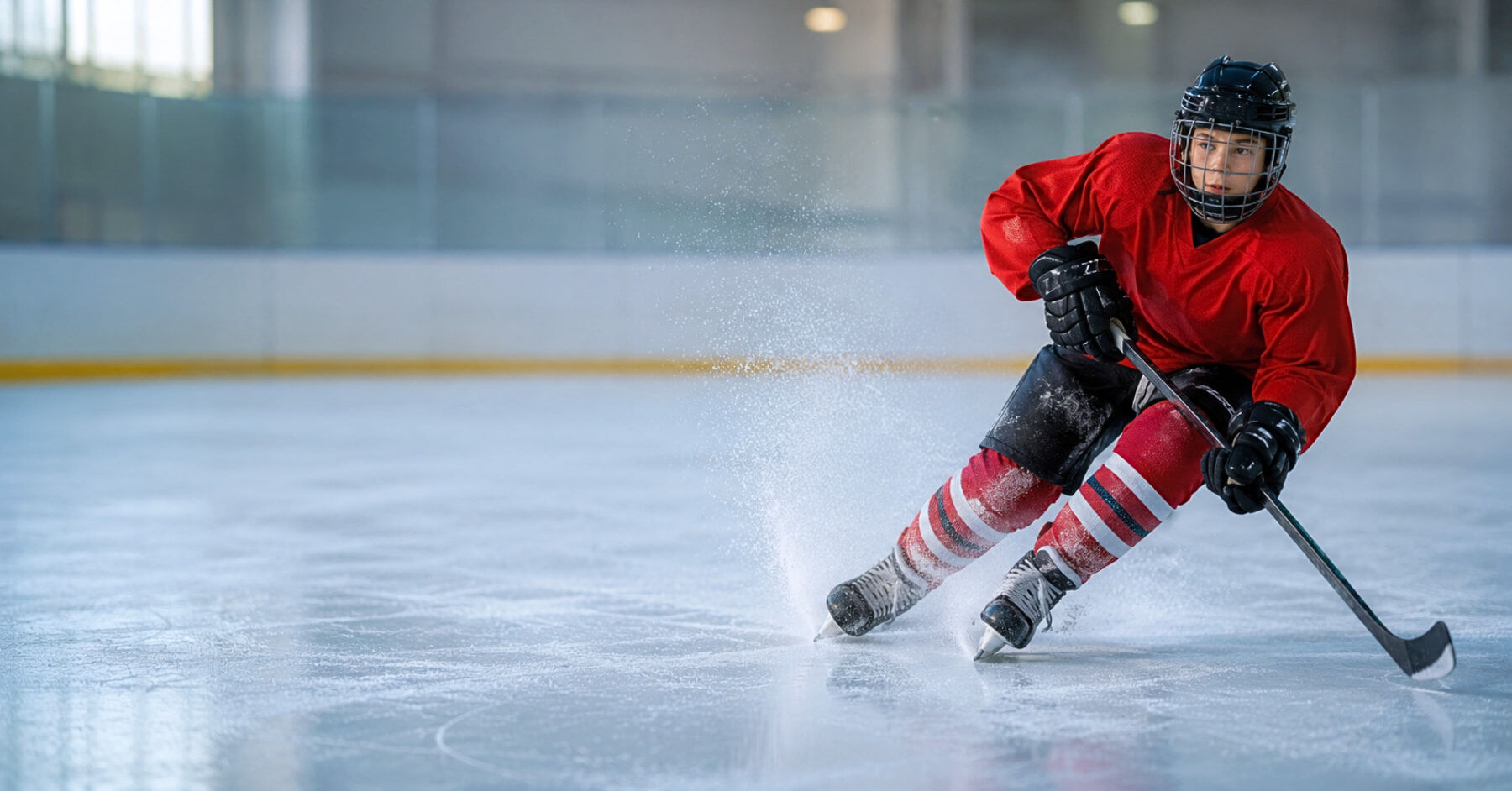 Young hockey player carving a hard turn on fresh ice